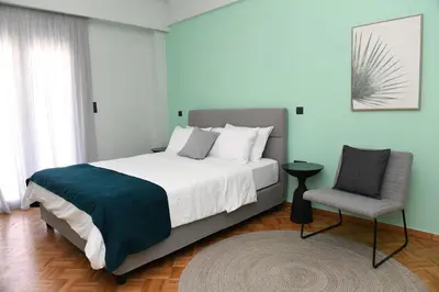 a bedroom with a large bed and a chair at Konstantina Apartment in Athens