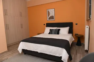 a bedroom with a large bed with an orange wall at Konstantina Apartment in Athens