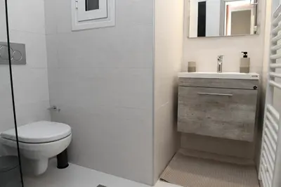 a white bathroom with a toilet and a sink at Alkmini Apartment in Athens