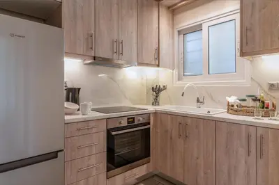 a kitchen with wooden cabinets and a sink and a window at Amazing sea view apartment in Lagonissi in Kalívia Thorikoú