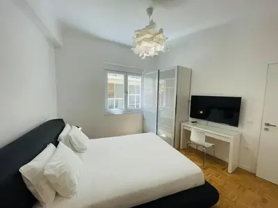 a bedroom with a white bed and a television at 3 bedroom New Modern Flat in the heart of Athens in Athens