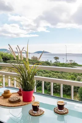 a table with two cups of coffee and a plant at Fantastic sea view one-bedroom apartment - Lagonissi in Lagonissi