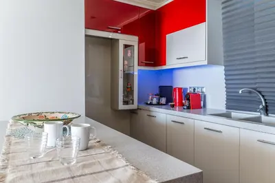 a kitchen with red and white cabinets and a table at Fantastic sea view one-bedroom apartment - Lagonissi in Lagonissi