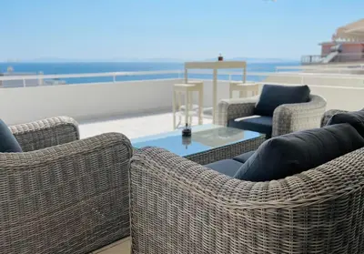 a group of wicker chairs and a table on the beach at Sea, La Vie in Saronida