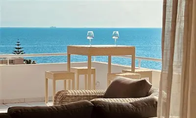 a living room with a table and chairs and the ocean at Sea, La Vie in Saronida