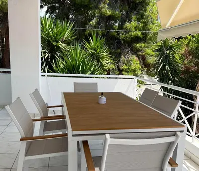 a wooden table and chairs on a balcony at Sea, La Vie in Saronida
