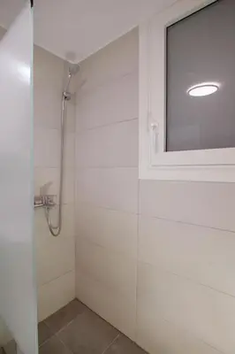 a shower with a glass door and a window at Beautiful apt near the sea by GHH in Athens