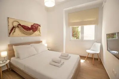 a white bedroom with a white bed and a window at Beautiful apt near the sea by GHH in Athens