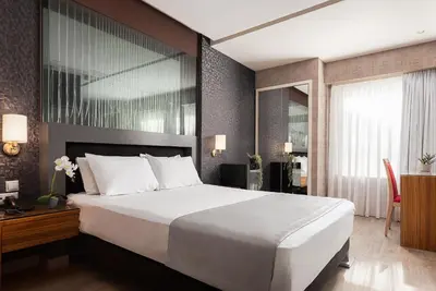 a bedroom with a large white bed and a desk at Lacoba Hotel in Athens