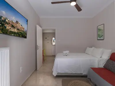 a white bedroom with a bed and a couch at AnapironPolemou5-Eleutheriou in Athens