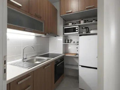 a kitchen with wooden cabinets and a sink and a refrigerator at AnapironPolemou5-Eleutheriou in Athens