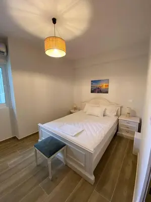 a bedroom with a large white bed and a lamp at Sea Through Apartment Anavissos in Anavissos