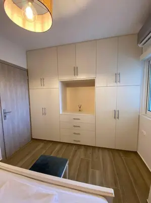 a large room with white cabinets and wood floors at Sea Through Apartment Anavissos in Anavissos