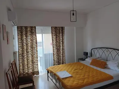 a bedroom with a bed and a table and a window at VOULIAGMENI RIVIERA center between Beach and Lake in Athens