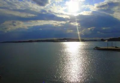 a large body of water with the sun in the sky at VOULIAGMENI RIVIERA center between Beach and Lake in Athens