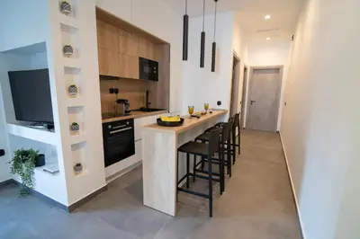 a kitchen with a counter and a bar with stools at White House Vouliagmeni 1- 2BD Free Parking, Next to the Sea in Athens