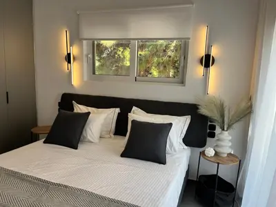 a bedroom with a large bed with two windows at White House Vouliagmeni 1- 2BD Free Parking, Next to the Sea in Athens