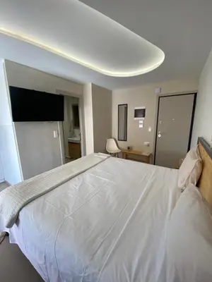 a bedroom with a large white bed with a flat screen tv at Anastasia Suite/byArtistUnknown in Vari