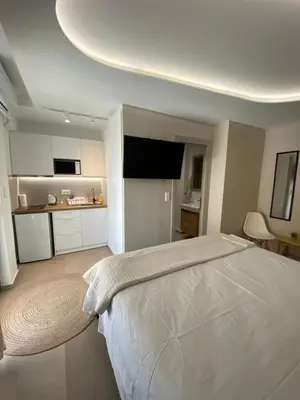 a bedroom with a large white bed and a kitchen at Anastasia Suite/byArtistUnknown in Vari