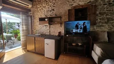 a living room with a tv on a brick wall at The Cellar Studios - by Avelink in Spáta