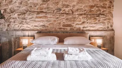 a bedroom with a stone wall with a bed with pillows at The Cellar Studios - by Avelink in Spáta