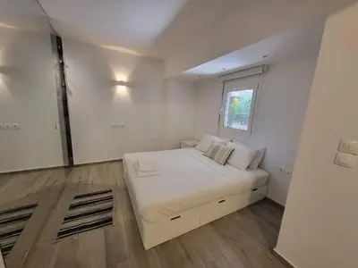 a white bedroom with a bed and a window at Apartment Near The Center Of Glyfada in Athens