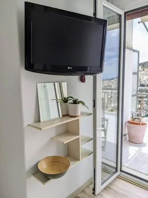 a flat screen tv hanging on a wall with shelves at Rooftop Studio with Acropolis & Sea view in Athens