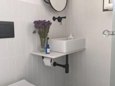 a bathroom with a sink and a vase of flowers on a shelf at Rooftop Studio with Acropolis & Sea view in Athens