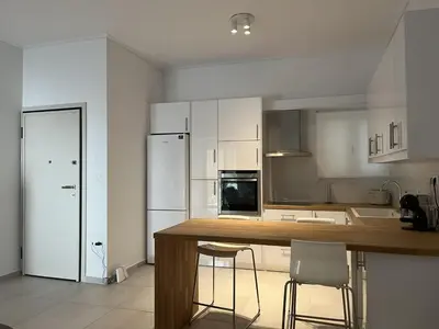 a kitchen with white cabinets and a wooden counter top at Apartment For 4 Ppl In N. Smirni in Athens