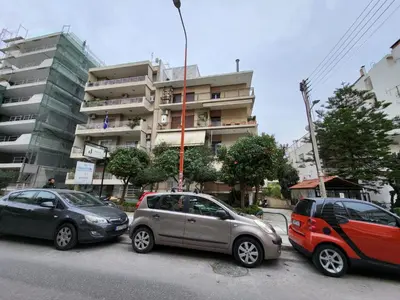 three cars parked in a parking lot in front of a building at Apartment For 4 Ppl In N. Smirni in Athens