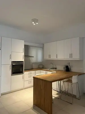 a kitchen with white cabinets and a wooden counter top at Apartment For 4 Ppl In N. Smirni in Athens