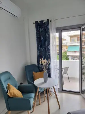 a living room with a blue chair and a table at Stylish studio in Glyfada in Athens