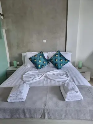 a large bed with white sheets and blue pillows at Stylish studio in Glyfada in Athens