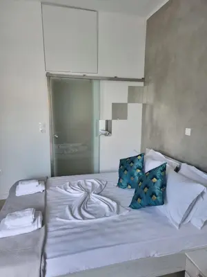 a bed with white sheets and blue pillows at Stylish studio in Glyfada in Athens
