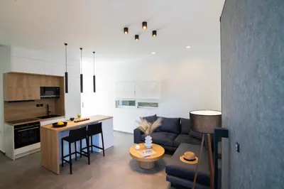 a living room and kitchen with a couch and a table at White House Vouliagmeni 2-Free parking-next to the sea in Athens