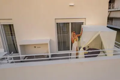 a woman standing on the balcony of a building at White House Vouliagmeni 2-Free parking-next to the sea in Athens