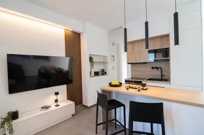 a kitchen with a bar with chairs and a tv at White House Vouliagmeni 2-Free parking-next to the sea in Athens
