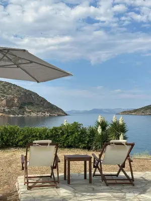 two chairs and a table and an umbrella and water at Coast Cottage Porto Rafti-Avlaki by BRP-Properties in Porto Rafti