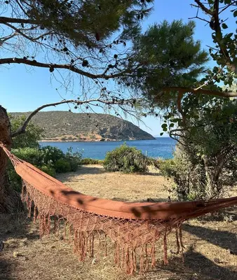 a hammock hanging from a tree in front of the ocean at Coast Cottage Porto Rafti-Avlaki by BRP-Properties in Porto Rafti