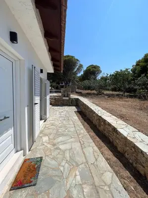 a stone walkway next to a building with a door at Coast Cottage Porto Rafti-Avlaki by BRP-Properties in Porto Rafti