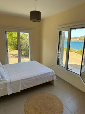 a bedroom with a bed and a view of the ocean at Coast Cottage Porto Rafti-Avlaki by BRP-Properties in Porto Rafti