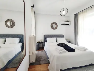two beds in a white room with a mirror at Varkiza Sea View Apartment - Free Parking in Vari