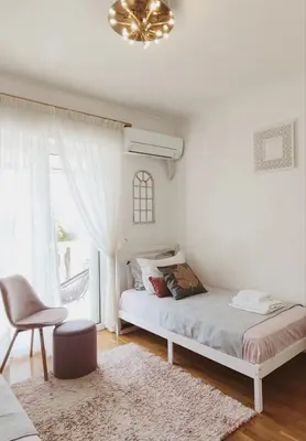 a bedroom with a bed and a chair and a window at Varkiza Sea View Apartment - Free Parking in Vari
