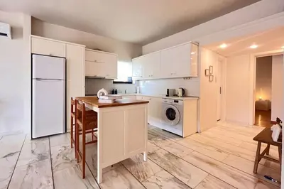 a kitchen with white cabinets and a table and a refrigerator at Pame Rentals - 1BD Apartment with Sea View in Athens