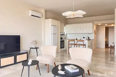 a living room with chairs and a tv and a kitchen at Pame Rentals - 1BD Apartment with Sea View in Athens