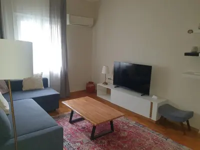 a living room with a blue couch and a tv at Family Apartment “Atene” in Athens