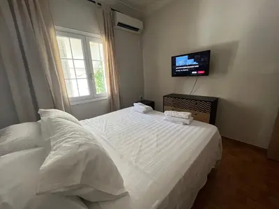a bedroom with a white bed with a tv on the wall at Family Apartment “Atene” in Athens
