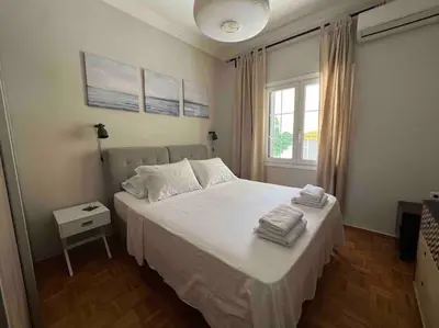 a bedroom with a bed with white sheets and a window at Family Apartment “Atene” in Athens