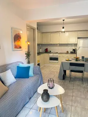 a living room with a couch and a kitchen at Garden Apartment with BBQ in the Athenian Riviera in Athens
