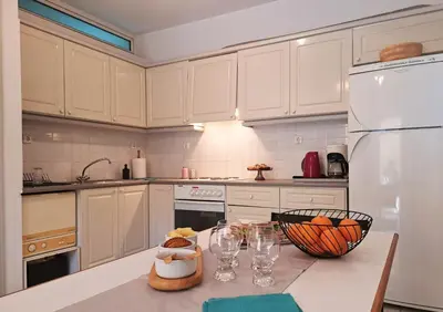 a kitchen with white cabinets and a table with wine glasses at Garden Apartment with BBQ in the Athenian Riviera in Athens